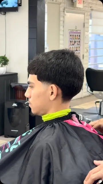 Young man in the chair with a textured fringe and clean taper around the ears
