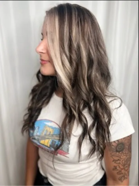 A woman with long, wavy dark brown hair and bright blonde face-framing highlights